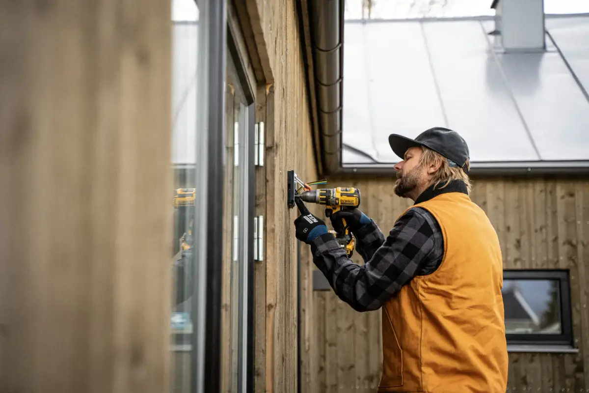 Contractor using a DeWalt drill on an exterior wall